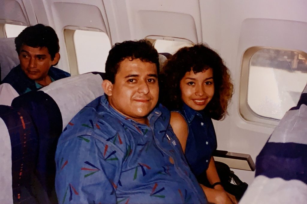 Oscar and Karen sitting beside each other in a plane.