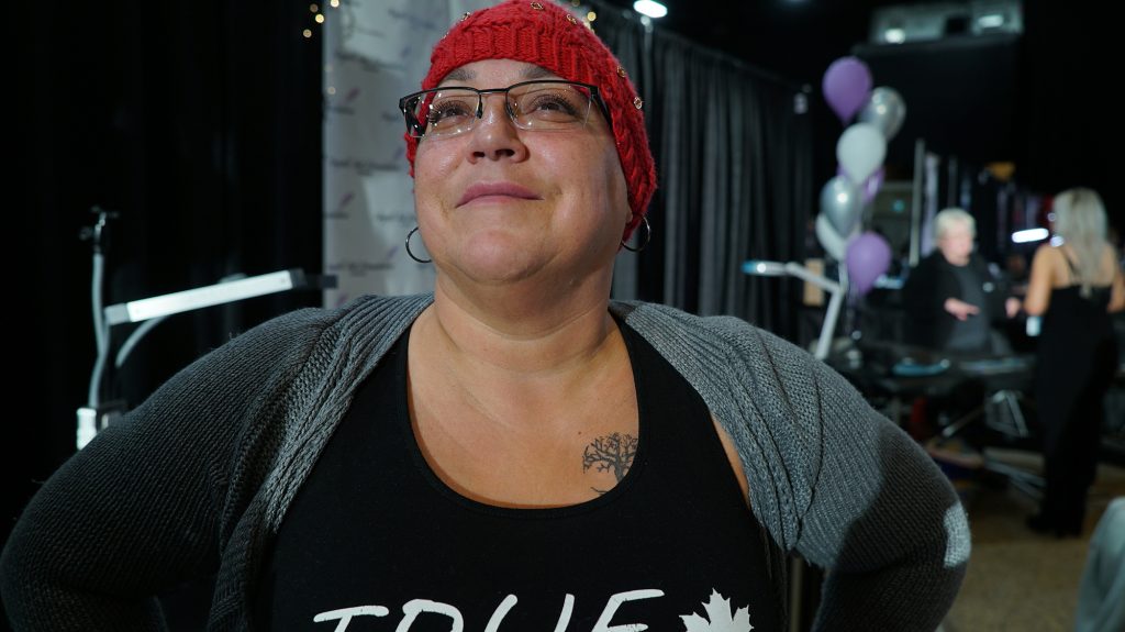 Bobbie Hornan smiles and shows off a small tree tattoo on her chest.