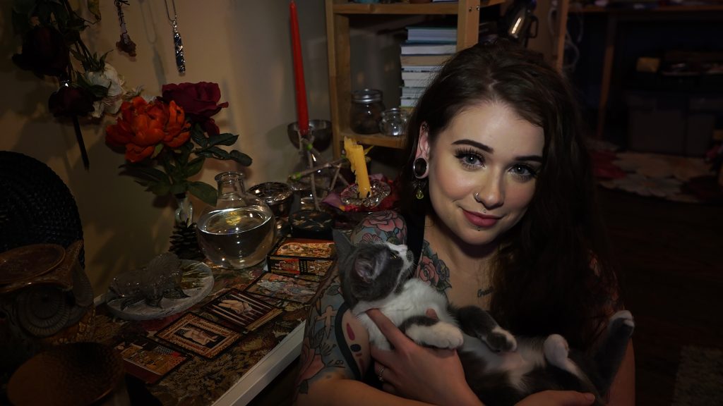 Medeiros holds her kitten, Basil, while sitting in front of her altar.