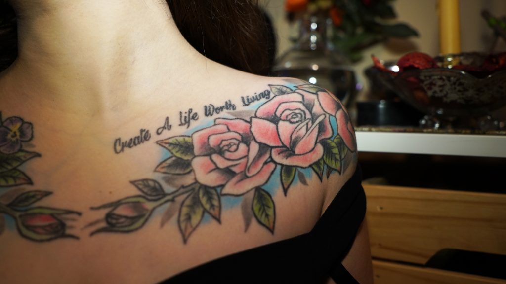 A close up of Medeiros' chest piece with script reading "Create A Life Worth Living."