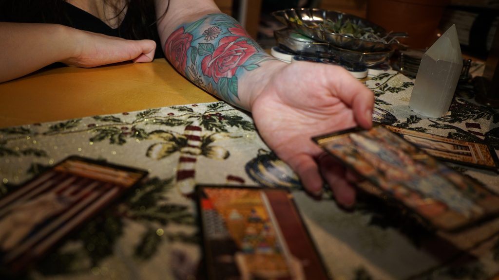 A close up of Medeiros' scar cover up while she turns over tarot cards.