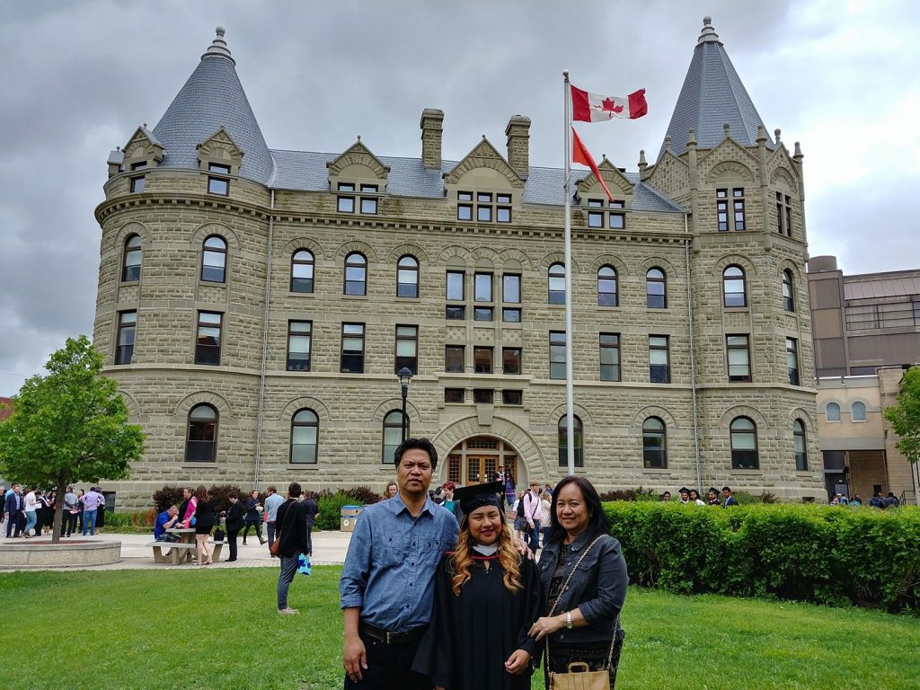 Alyssa and her parents standing in front of The University of Winnipeg.