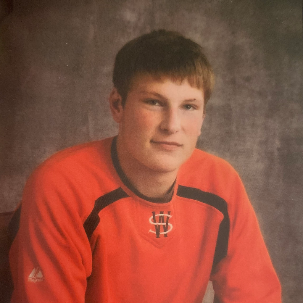 A portrait of Cody Rempel, a young teenage boy, in an orange jersey.