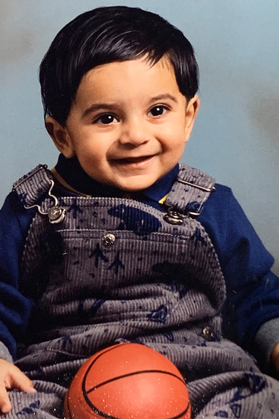 Raj as a toddler with a small basketball in his lap.