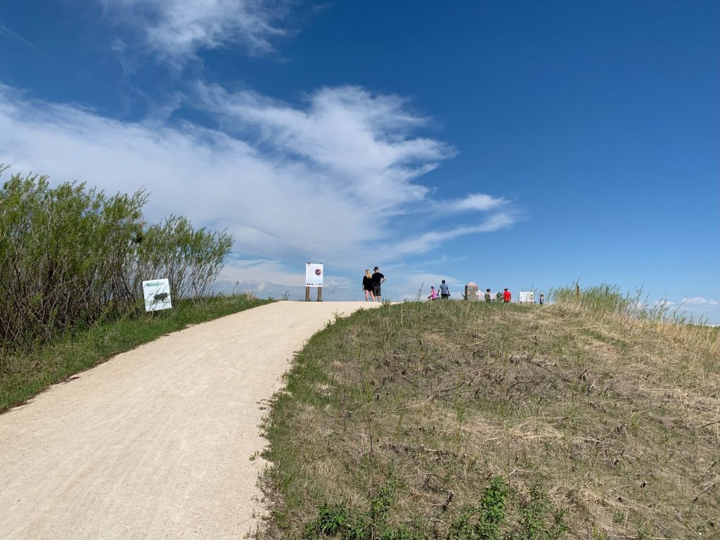 Gravel path going up a hill with signs along the left side.