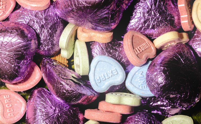 close up of heart chocolates in purple foil and hard heart candy that have different words on them.