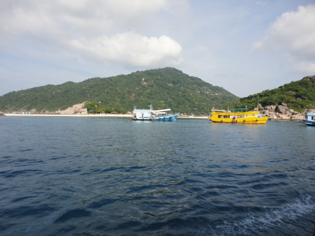 Boats on the open water with green hills behind them.