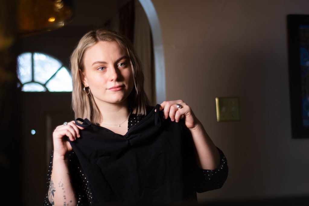 Sophie Ashton holds up her body suit against her body.