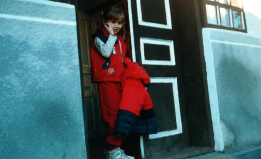 Liliya as a young girl standing in a doorway looking nervous.