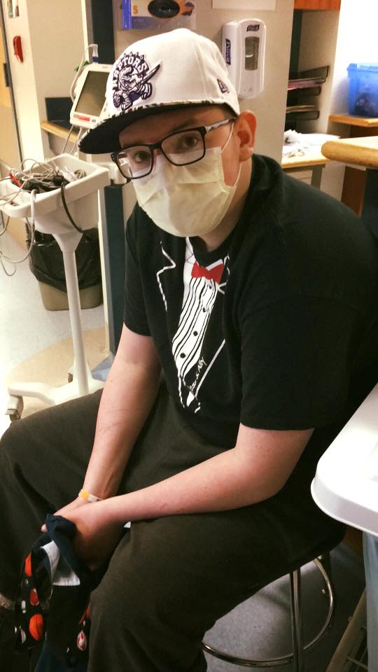Ross sitting in the hospital wearing a surgical mask. 