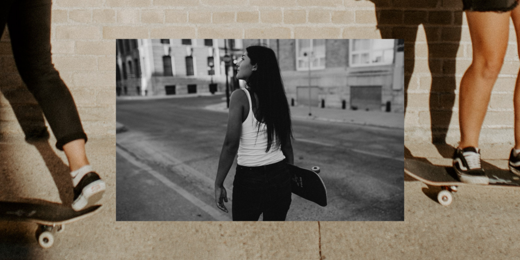 Black and white photo of girl with skateboard, walking downtown. Layered behind is another skateboard photo of two girls' feet on their skateboards. 