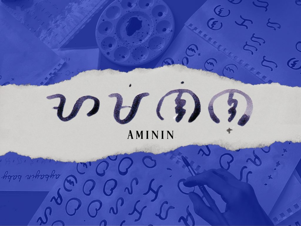 Hand painted Baybayin script spelling out "AMININ" on torn paper, blue background with faint handwriting and art elements.