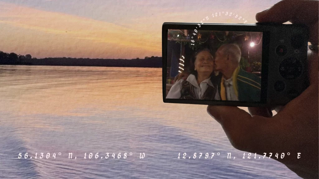 A photo of a digicam with John's grandparents on screen. The background is a sunset on a lake in Manitoba.