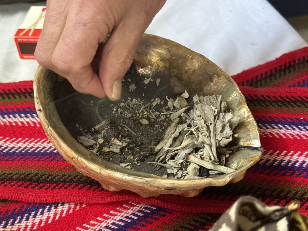 A photo of John McKay separating the ember from the sage, allowing the flame to recede on its own.