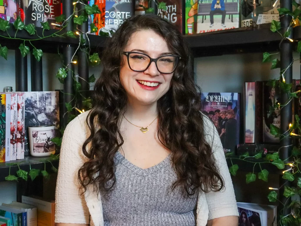 Emma Ivison is standing in front of her bookshelves.