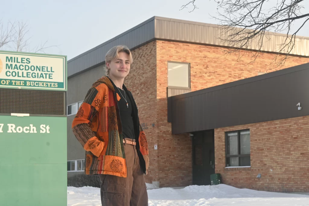 Kaiden Peters stands outside his former high school. 