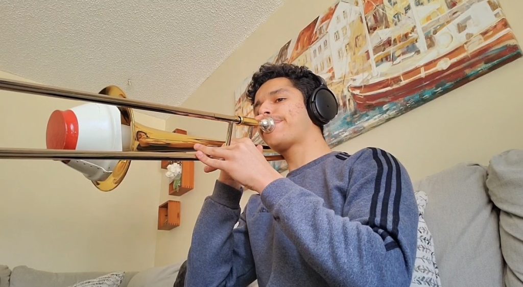 Man wearing headphones playing the trombone.