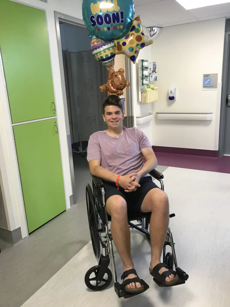 Spencer sitting in a wheelchair with balloons.