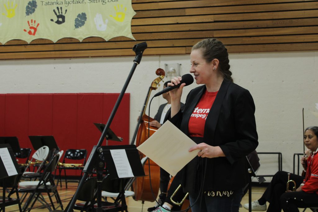 Woman in gymnasium holding a microphone.