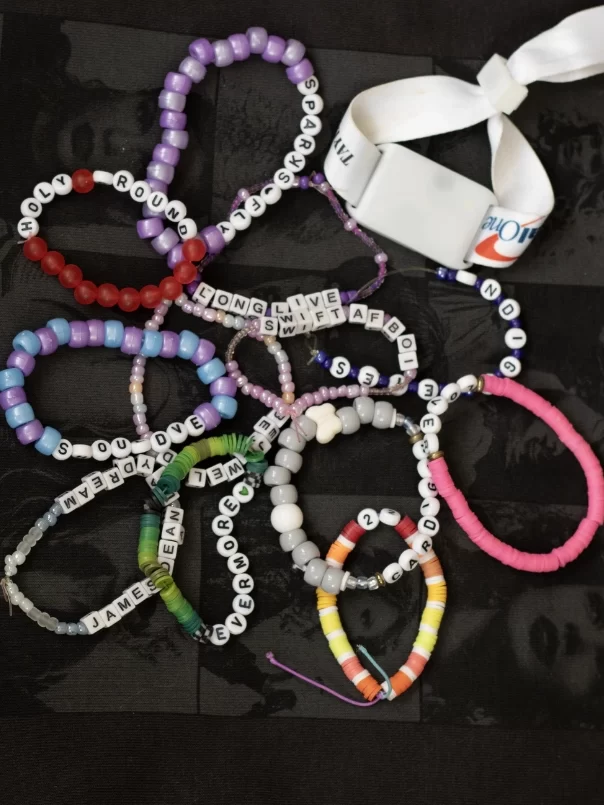 An array of handmade friendship bracelets on top of a Taylor Swift hoodie