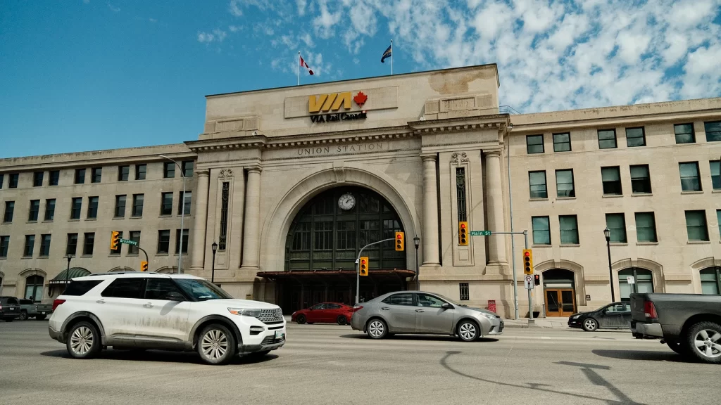 Several lanes of traffic pass by Union Station at Main Street and Broadway Avenue in Winnipeg.